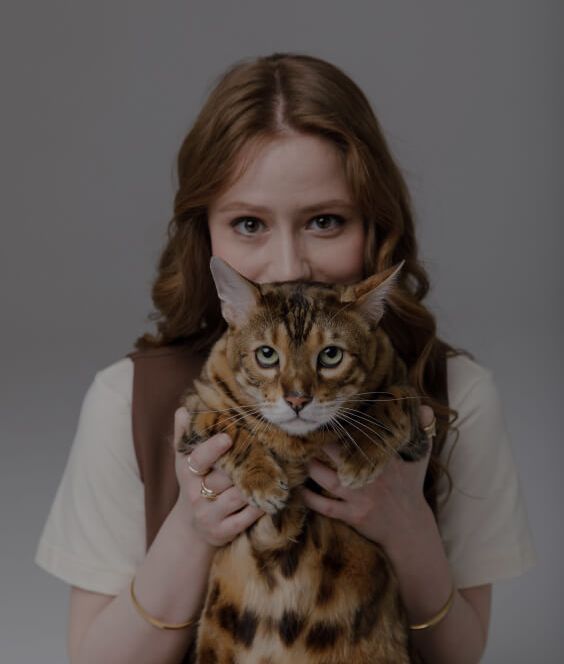 Девушка держит перед собой бенгальскую кошку